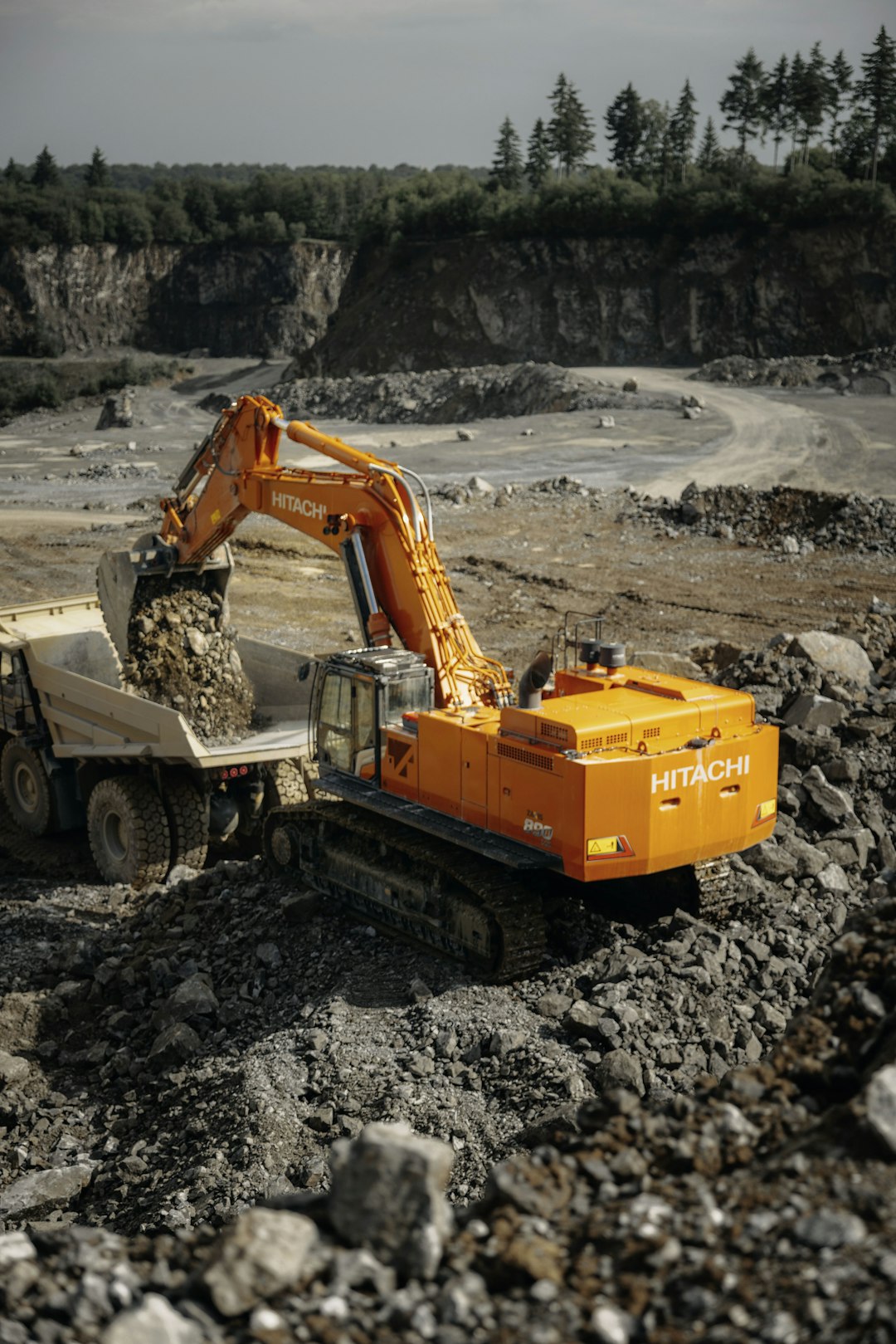 Ein Hitachi ZX890LCH-7 Bagger lädt Gesteinsbrocken in einen Muldenkipper in einem Steinbruch
